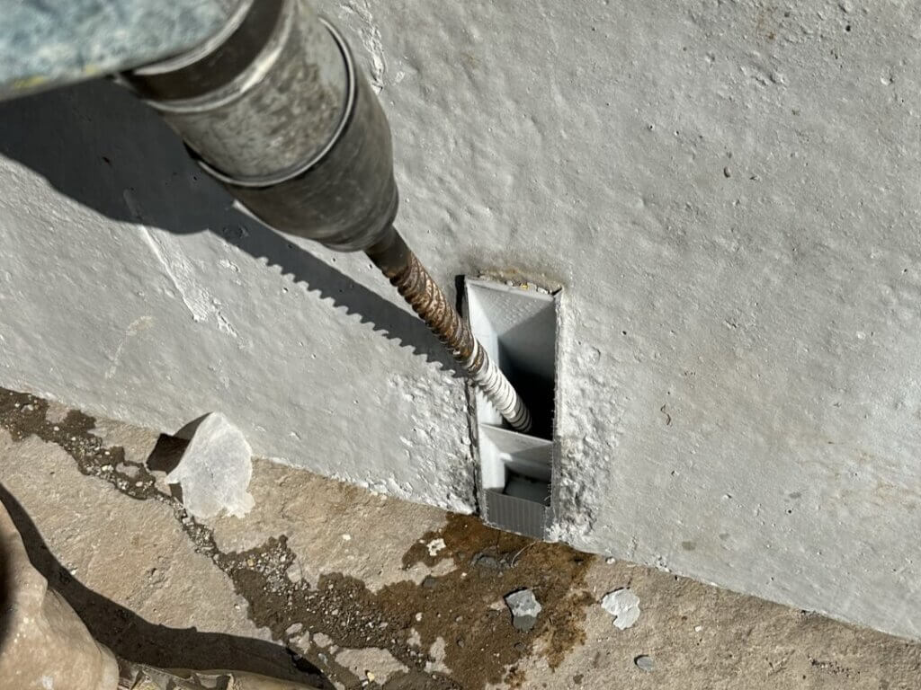 Installer drilling through a DAB wall panel base connection for bolted installation to a foundation.